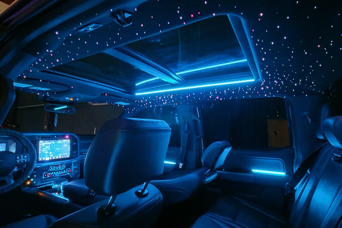 Blue ambient lighting through the doors, dash and sunroof of a Ford F-150 with a starlight headliner