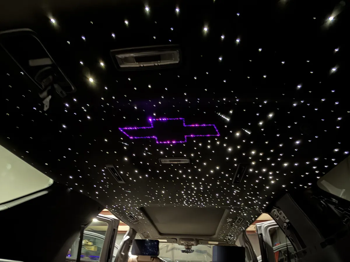 Purple fiber-optic Chevrolet bowtie logo surrounded by stars in an SUV headliner