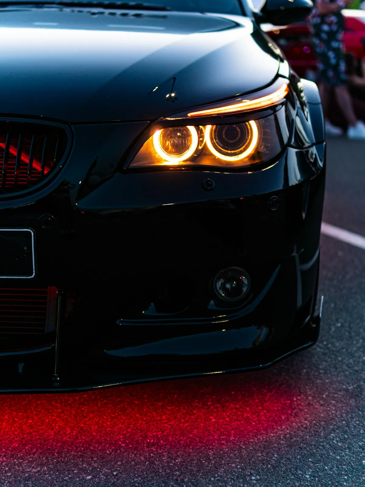 Amber halo rings glowing in the headlights of a black sedan at night