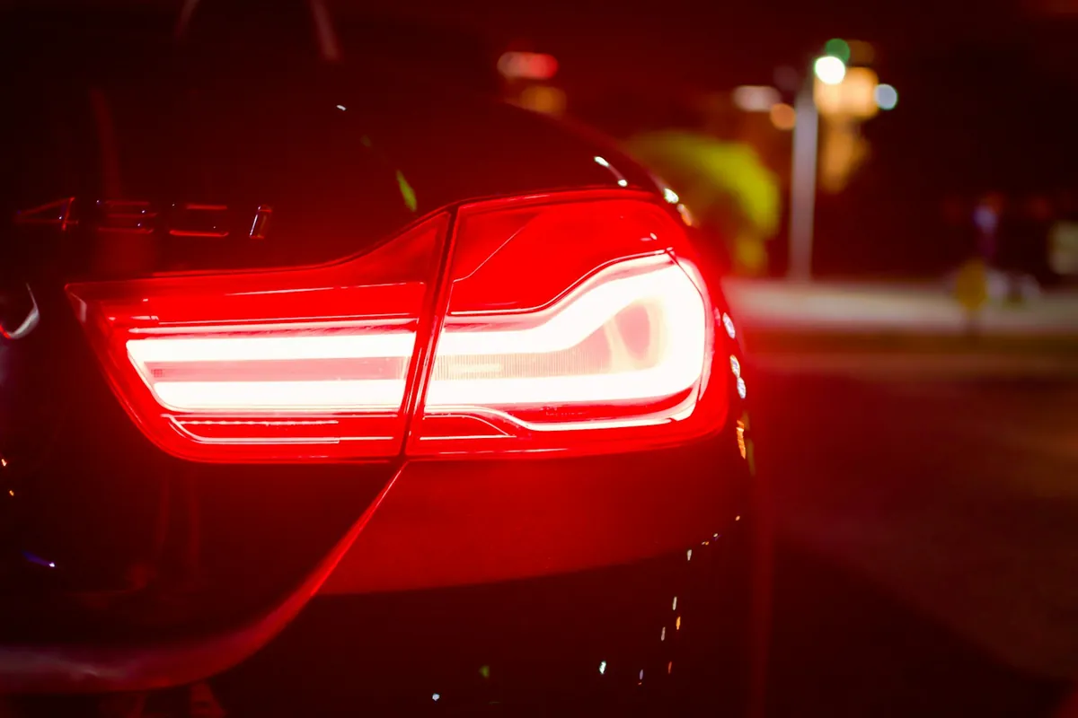Red LED tail light glowing on a car at night