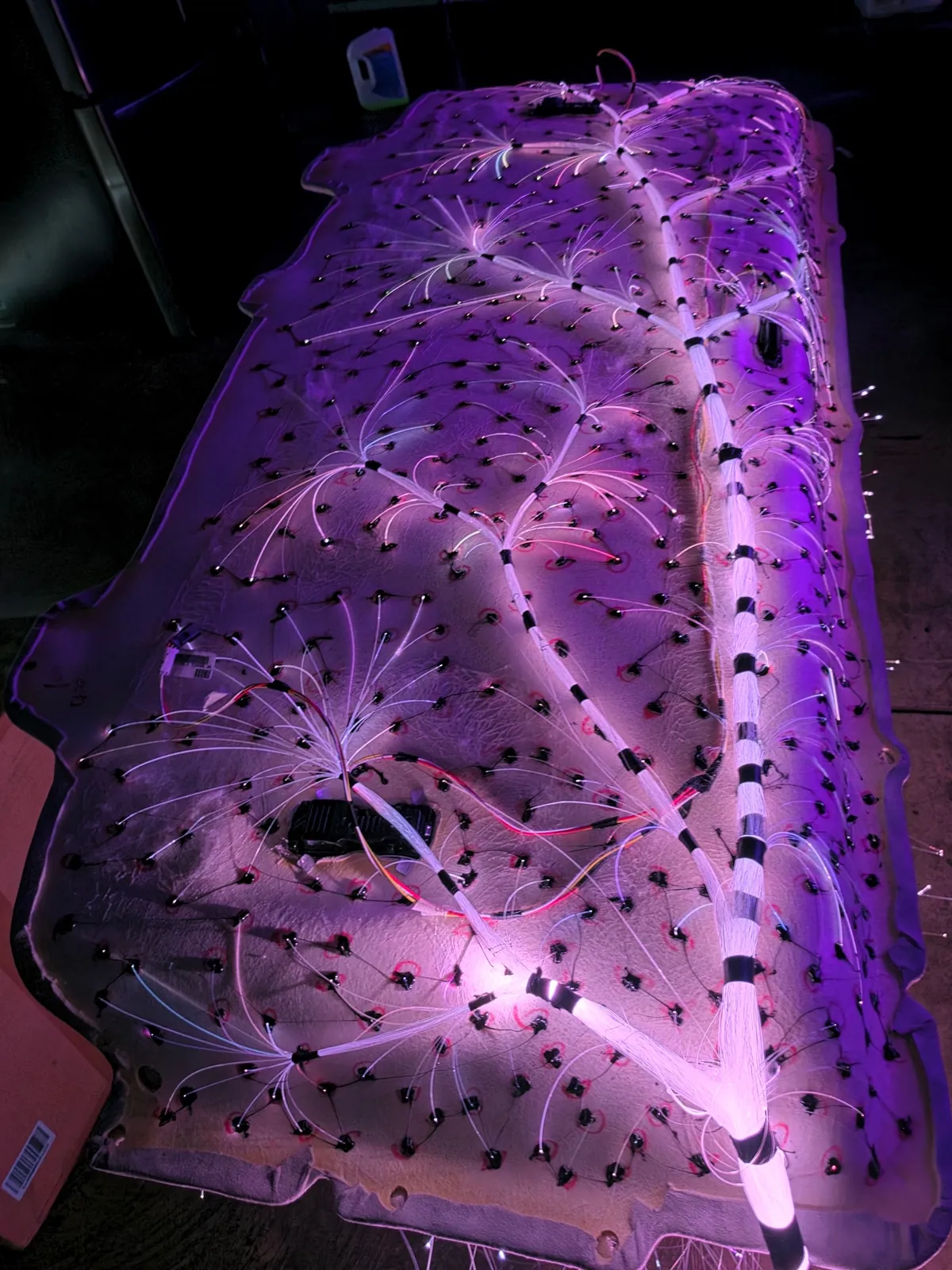 Back of a headliner board with hundreds of fiber-optic strands routed by hand