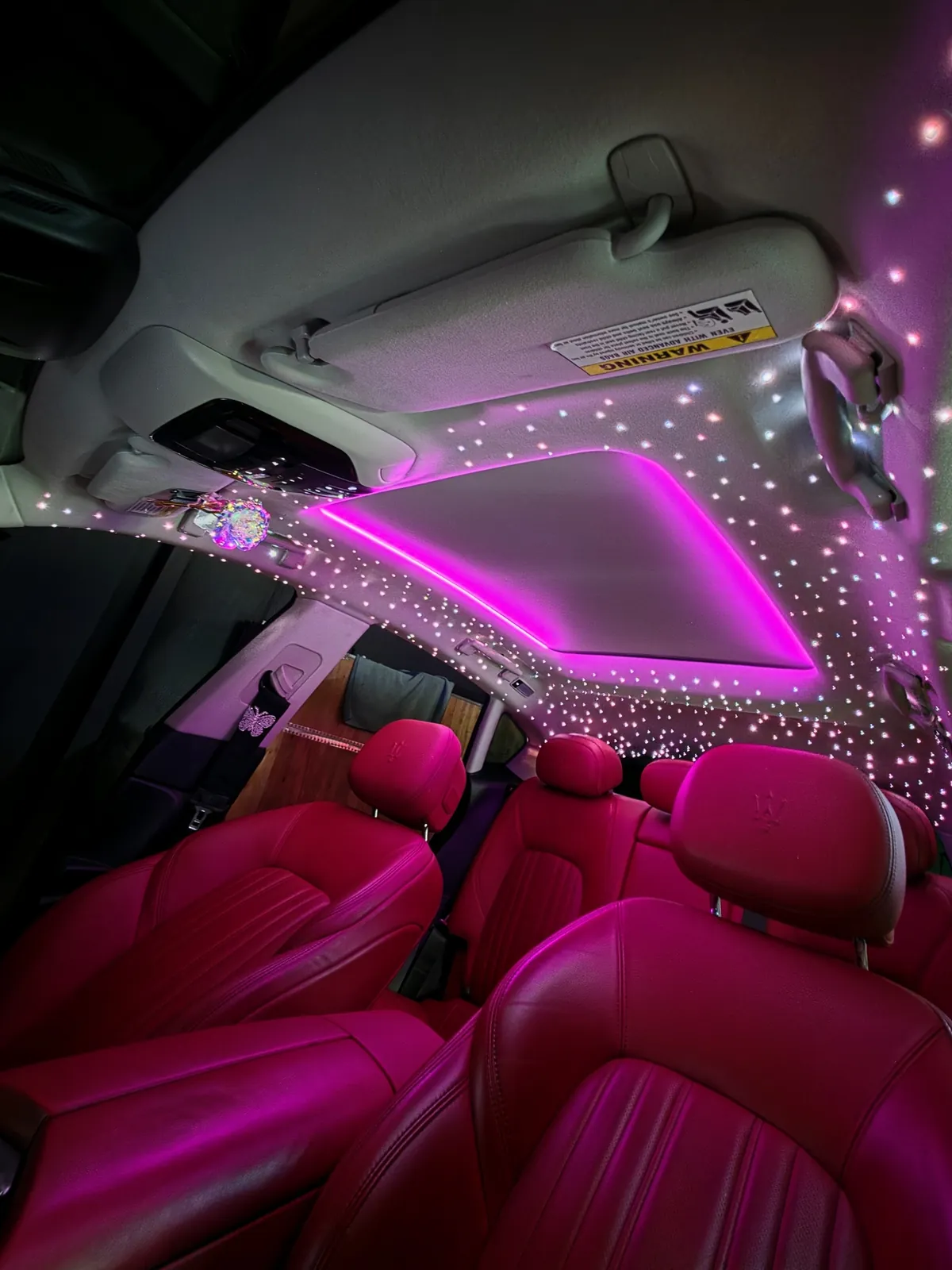 Pink sunroof ambient strip and starlight headliner above pink leather seats in a Maserati