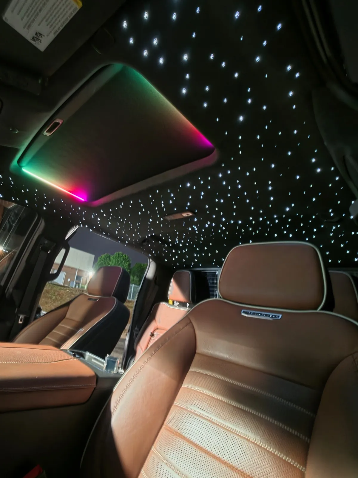 Fiber-optic starlight headliner and a lit sunroof surround above saddle leather seats in a pickup
